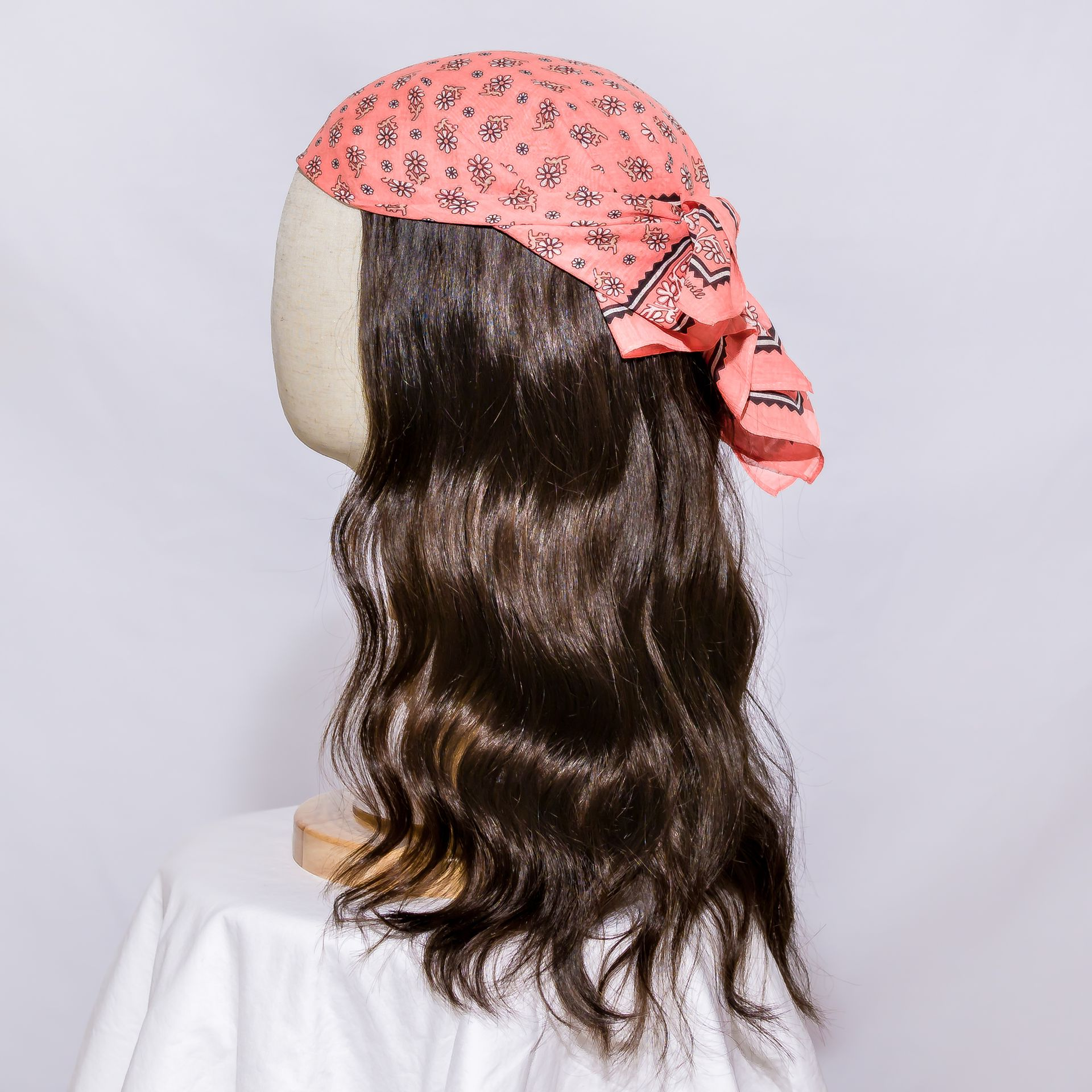 Woman with long, straight brown hair wearing a black top, posed in front of a white, paneled wall.