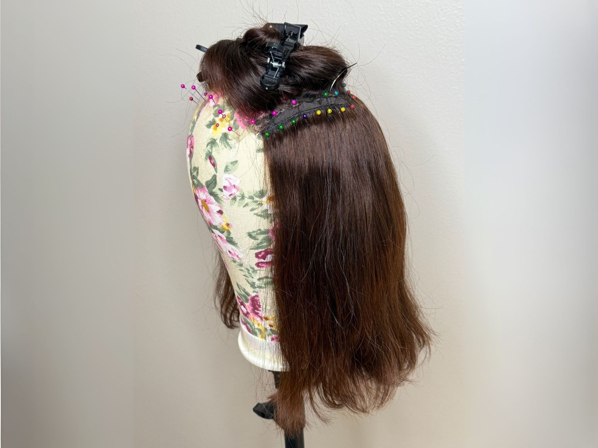Brown bob wig on a mannequin head. The wig has bangs and a side part.