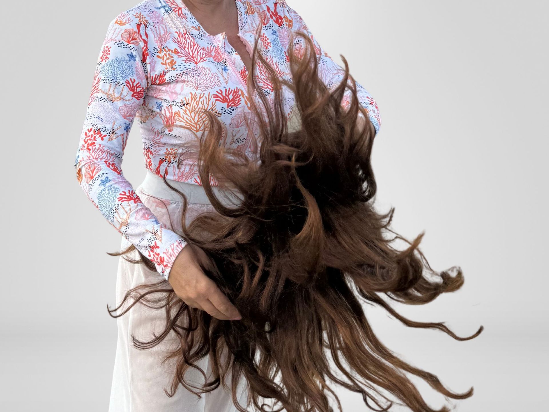 Woman comparing her hair to a color swatch board, looking for a perfect match. White interior with plant and mirror.