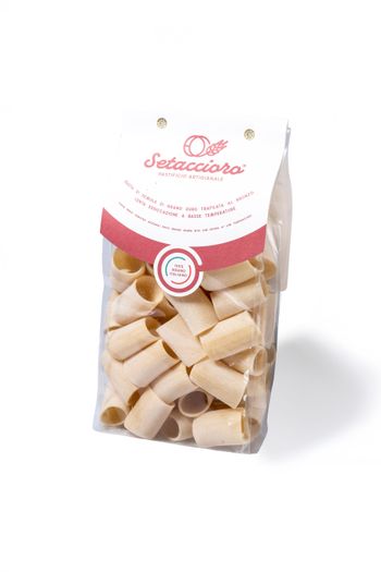 Sacchetto trasparente di pasta arrotolata beige con etichetta rosa e bianca su sfondo bianco.