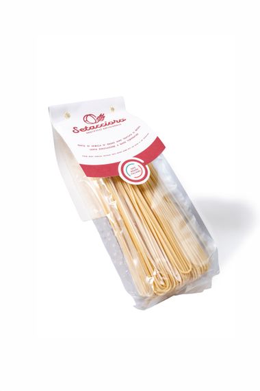 Sacchetto di plastica trasparente contenente grissini lunghi con etichetta rossa e bianca su sfondo bianco.