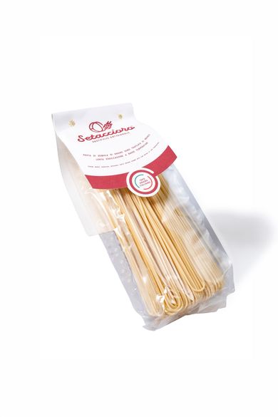 Sacchetto trasparente di pasta arrotolata beige con etichetta rosa e bianca su sfondo bianco.