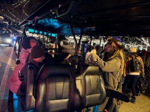 Beige golf cart parked on a gravel path near trees.