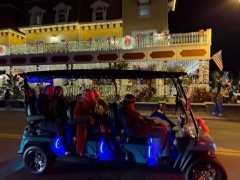 White golf cart on a paved path winding through a golf course under a clear, blue sky.