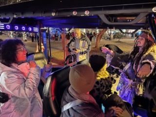 People on a decorated golf cart with a Jack Sparrow impersonator. Night setting with lights.