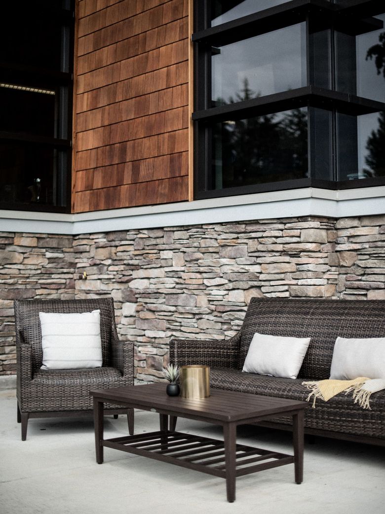 A stone wall with a couch and chairs in front of it