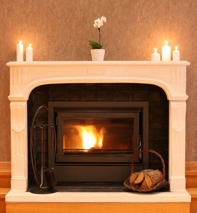 A fireplace with candles and a basket of logs