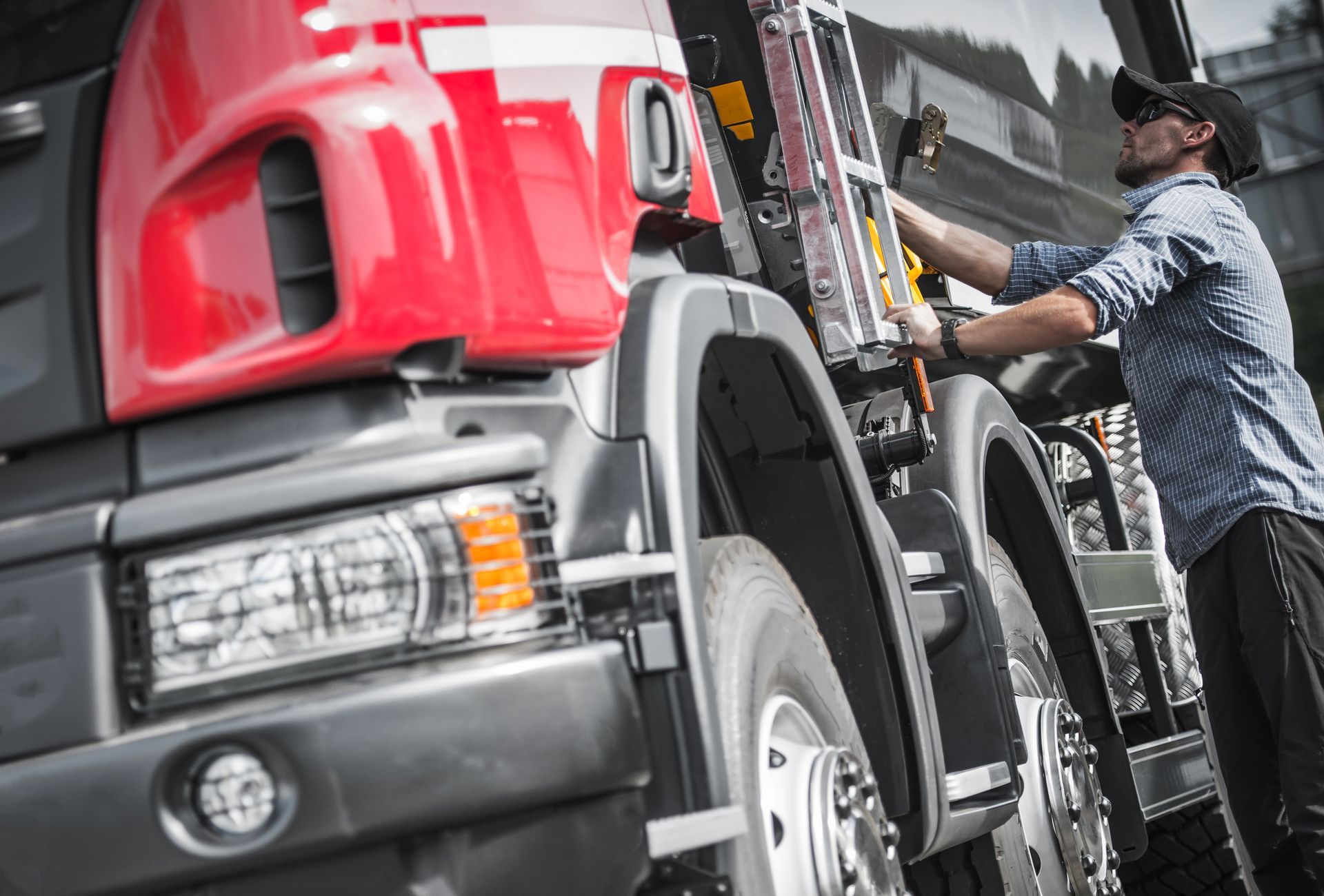 A man is working on a red semi truck.