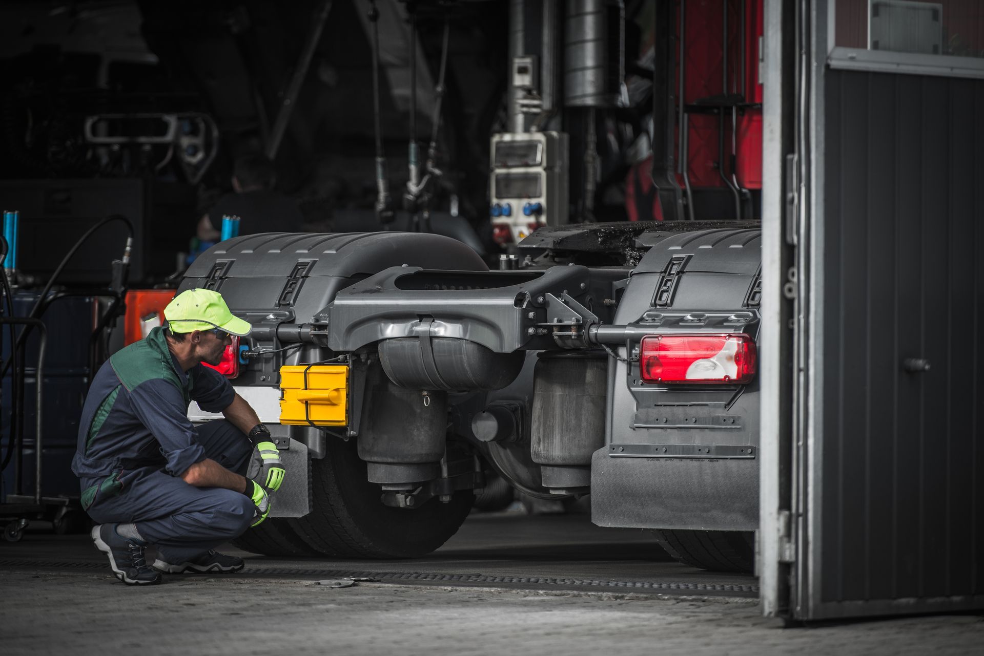 A man is working on a semi truck in a garage.