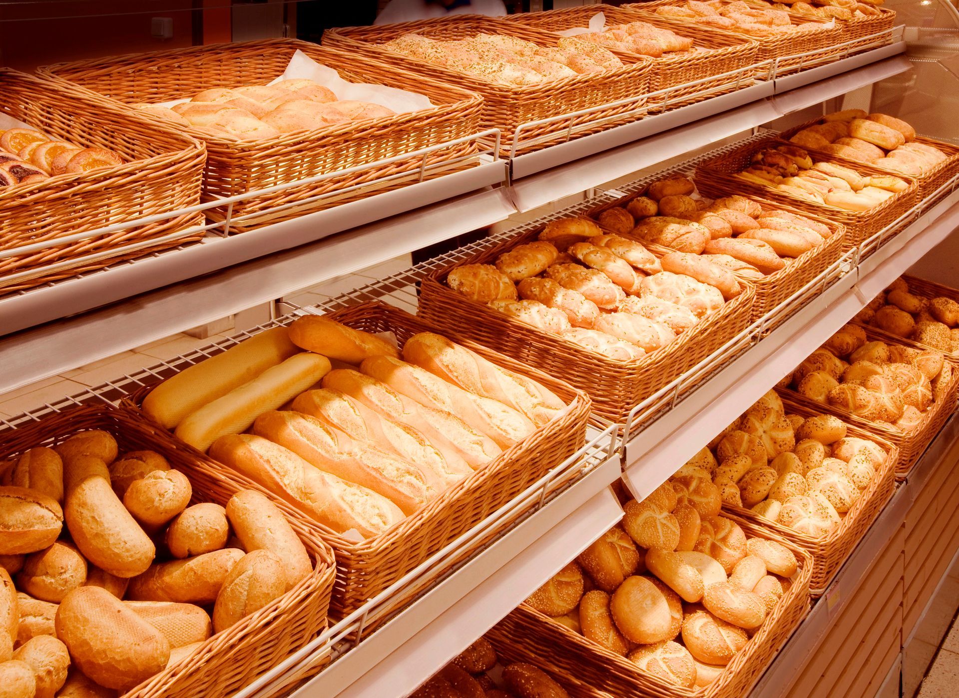Scaffali che espongono vari tipi di pane cotto in cestini di vimini.