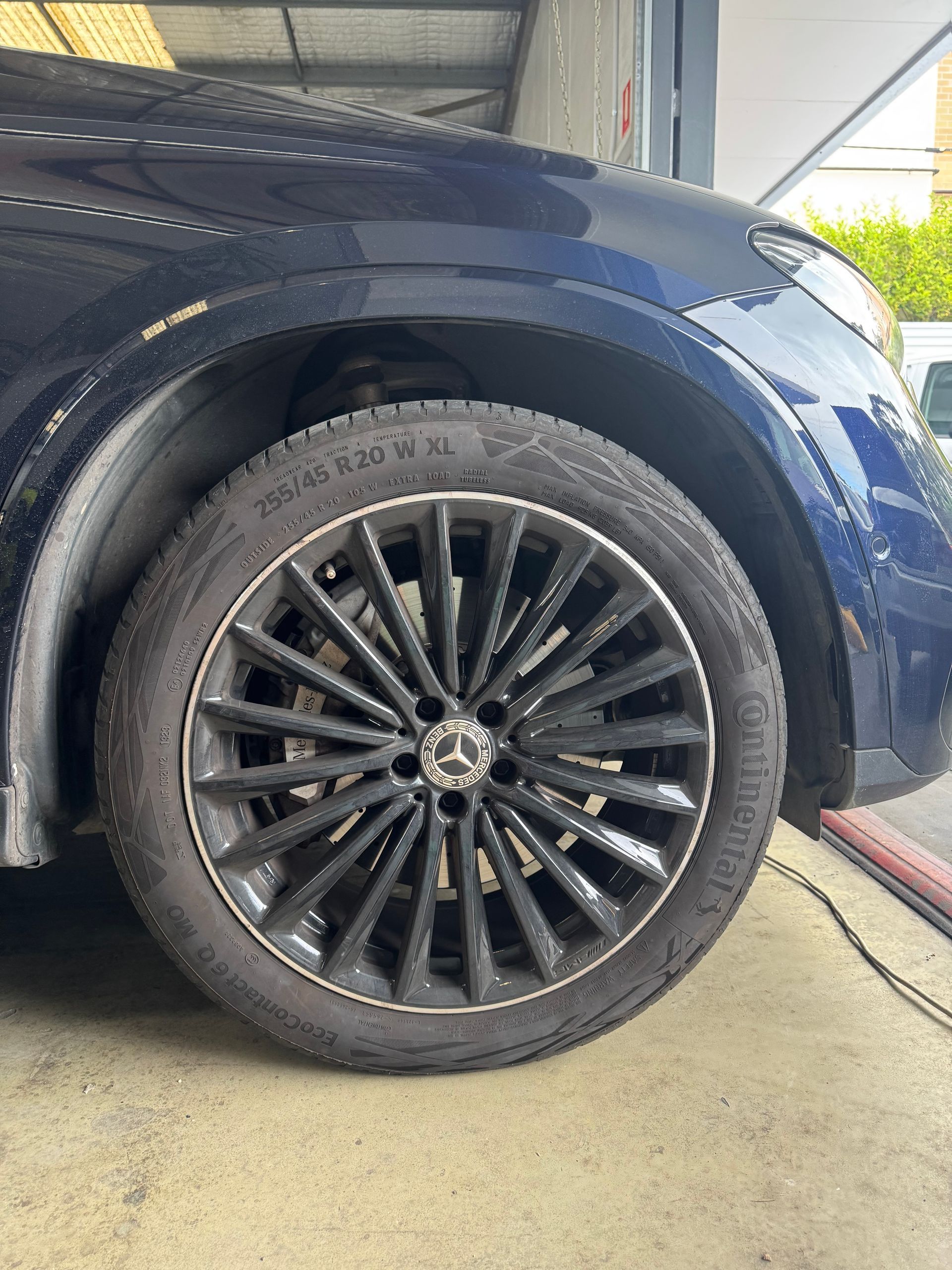 Dark blue Mercedes SUV tire, black rim, Continental tire.