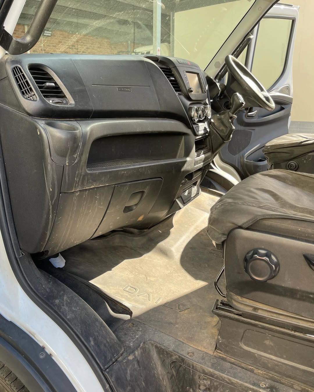 Interior of a white commercial van, showing dashboard, driver's seat, and floor.