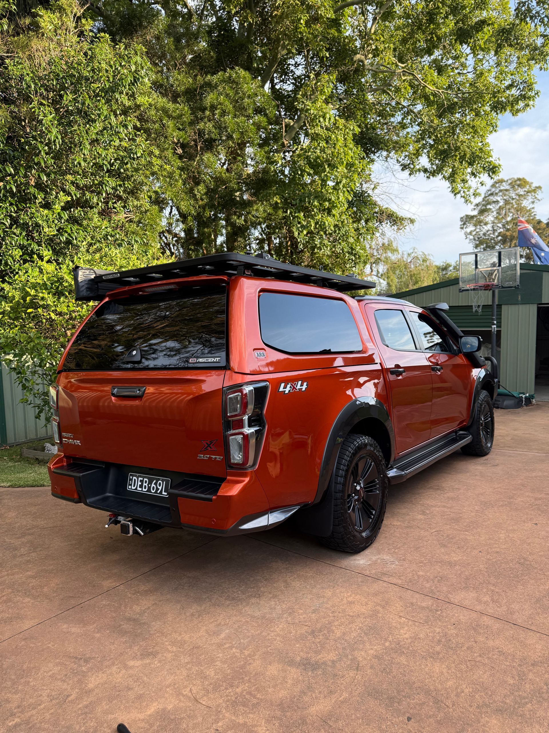 Red pickup truck with black accents, off-road modifications, and a canopy parked outside.