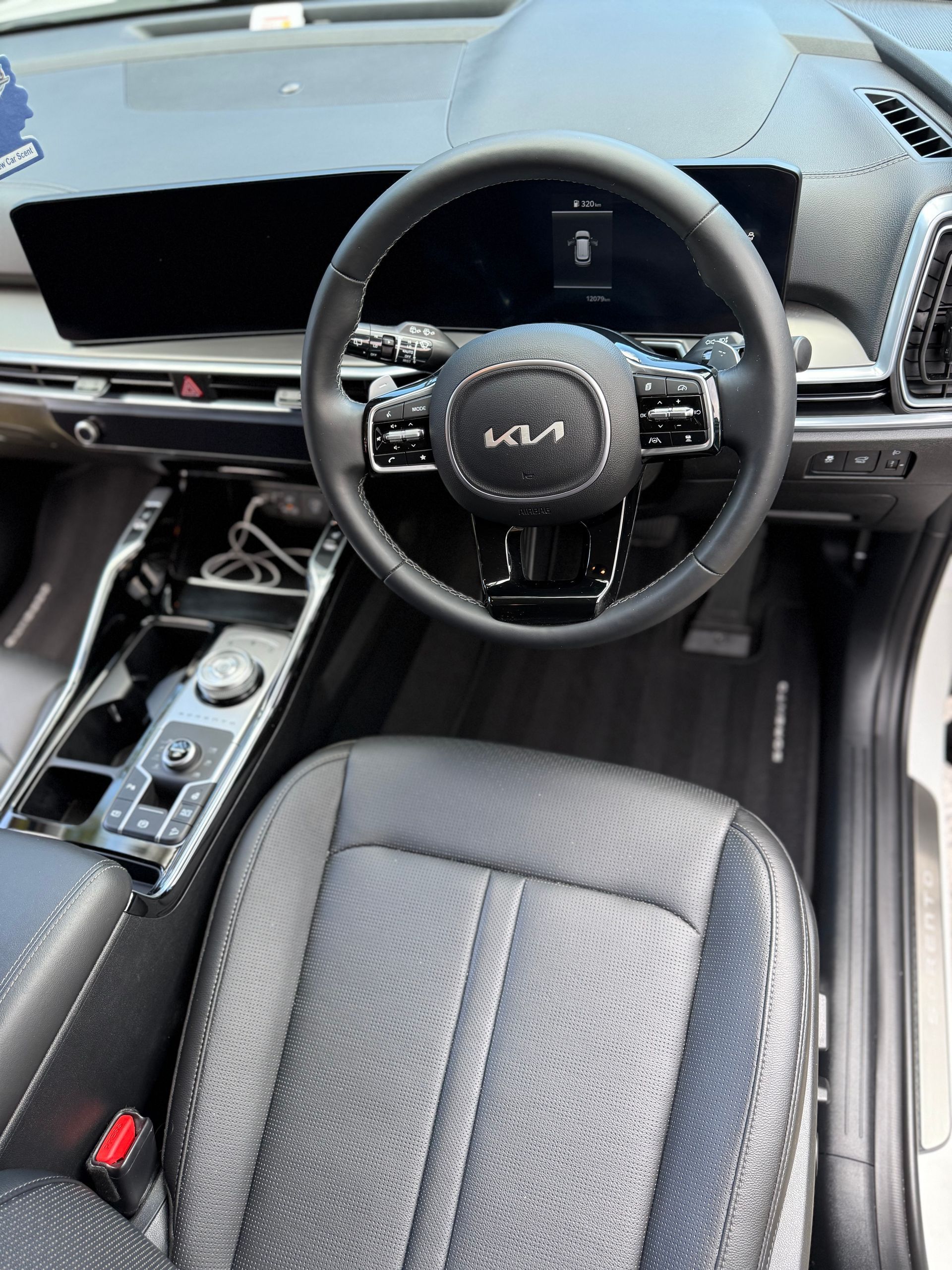 Interior of a Kia vehicle: black leather seats, steering wheel with Kia logo, digital dashboard, and console.