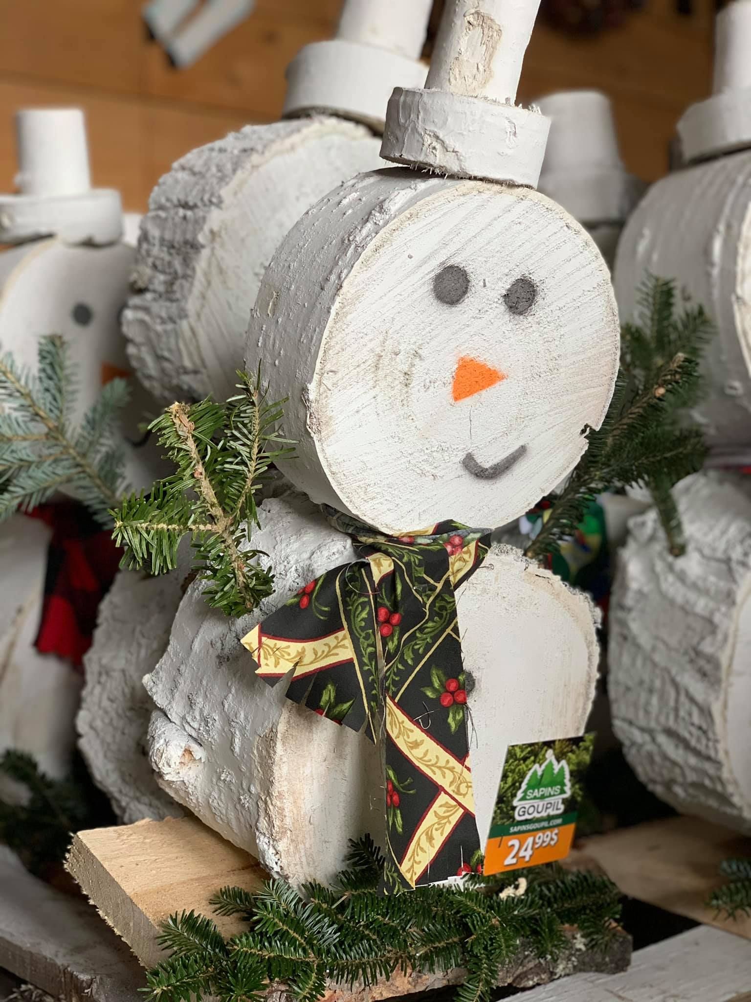 Un bonhomme de neige en bois est assis sur une table en bois.