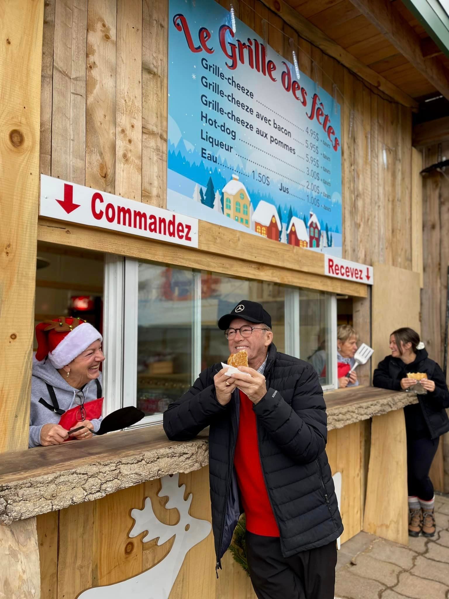 Un homme mange un hot-dog dans un stand de nourriture.