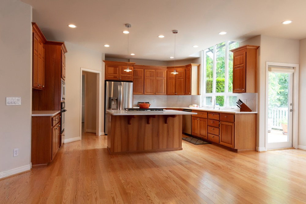 an empty kitchen with wooden cabinets and hardwood floors .