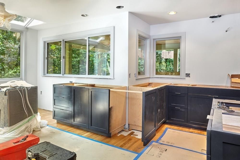 a kitchen is being remodeled with black cabinets and white walls .