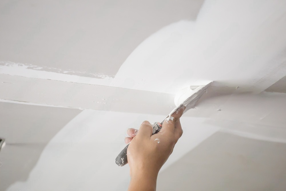 a person is painting a ceiling with a spatula .