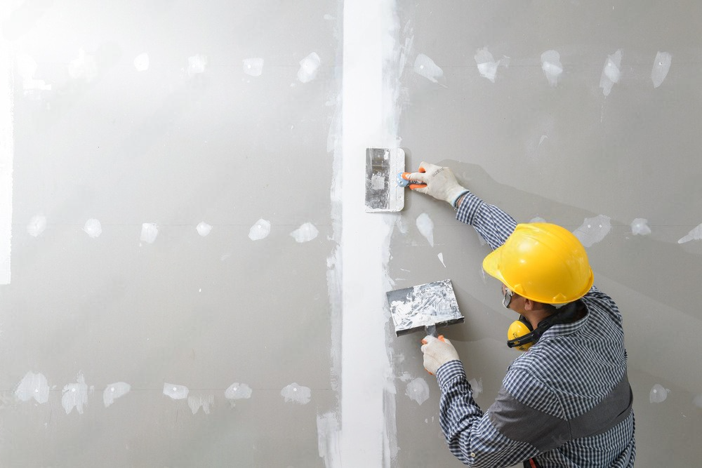 a man is plastering a wall with a spatula .