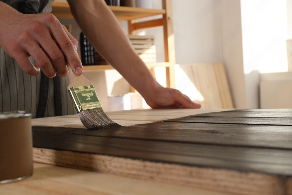 a person is painting a piece of wood with a brush .