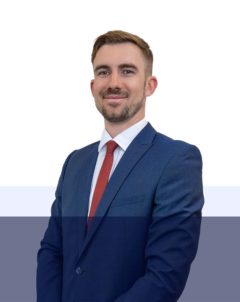 A man in a suit and tie is standing in front of a white background.