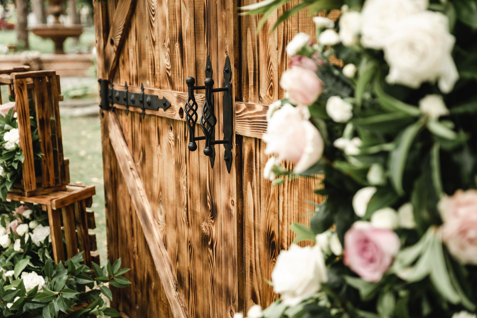 Wooden door with ornate black hardware, decorated with flowers.