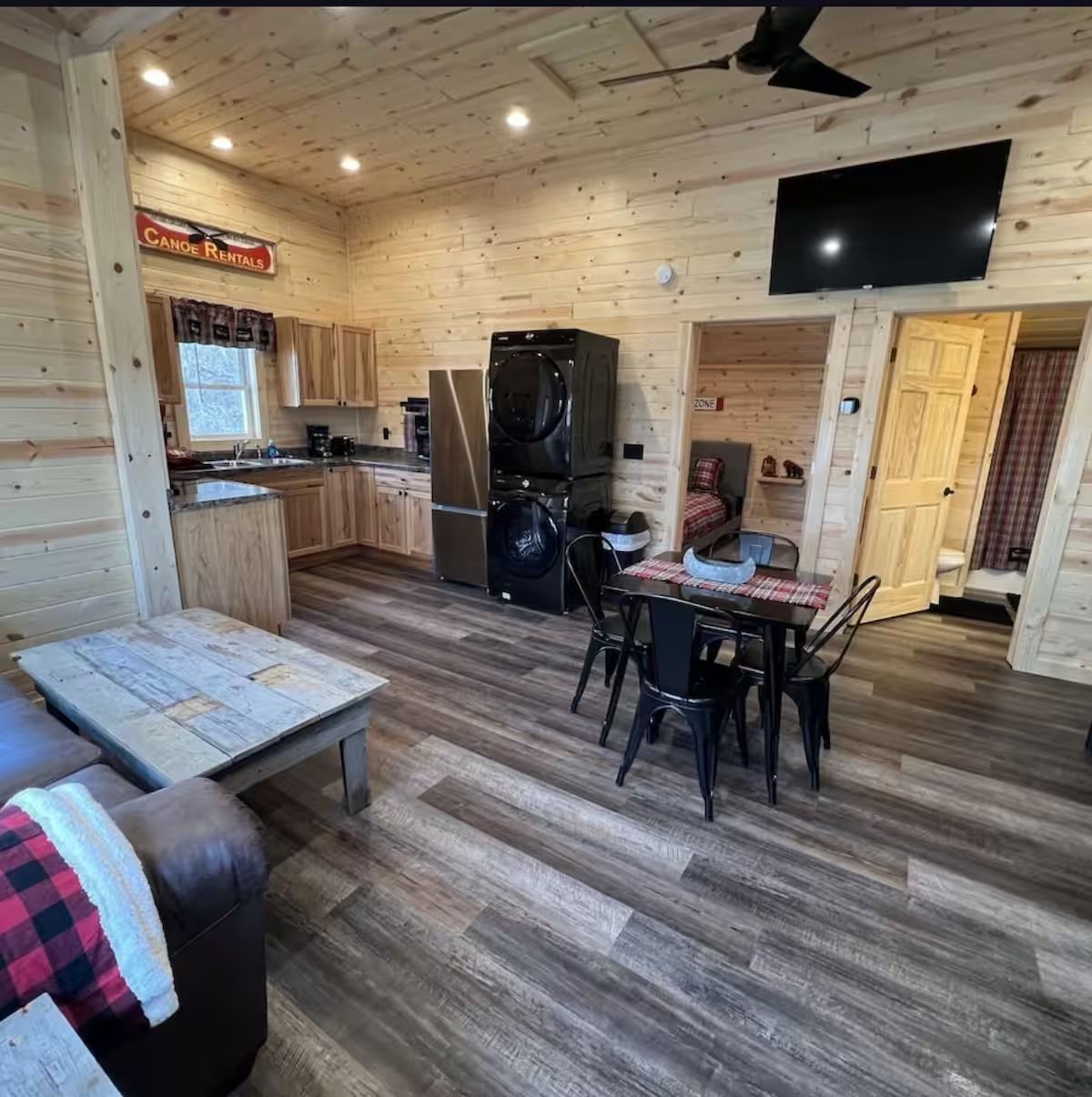 Cozy cabin interior with wood paneling, kitchen, dining area, and living room.