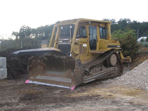 A yellow bulldozer is parked in a gravel lot.