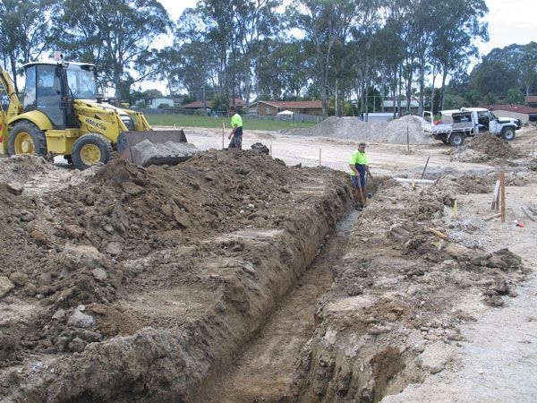 A yellow bulldozer is digging a trench in the dirt