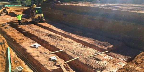 A construction site with a lot of dirt and a man standing in the dirt.