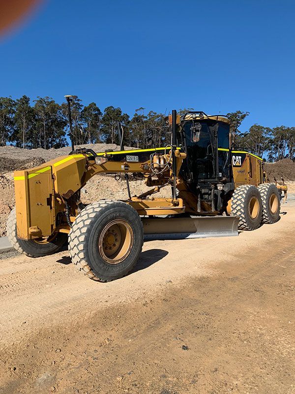 A yellow tractor is parked on the side of a dirt road.