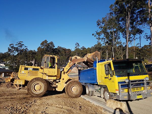 A bulldozer is loading dirt into a dump truck.