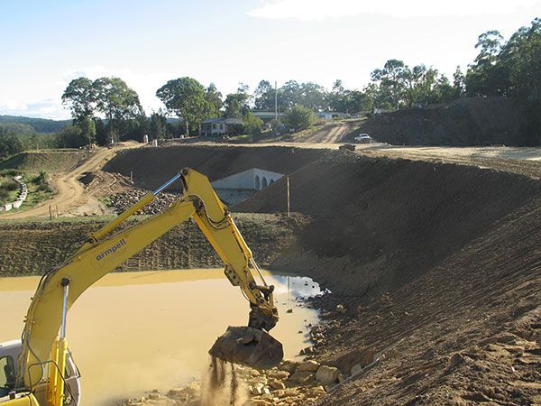 A yellow excavator is digging in a body of water