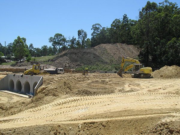 A construction site with a lot of dirt and trees in the background