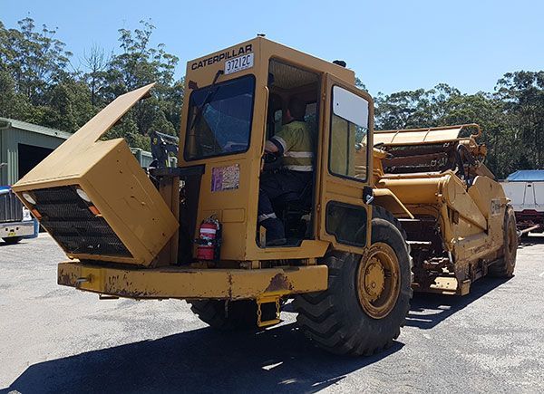 A yellow caterpillar tractor is parked in a parking lot