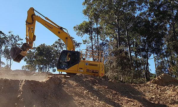 A yellow excavator is digging a hole in the dirt.