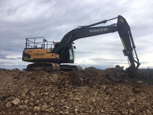 A volvo excavator is sitting on top of a pile of rocks.
