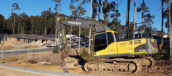 A yellow and black volvo excavator is parked on the side of the road.