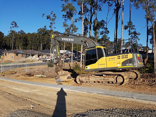 A yellow and black volvo excavator is parked on a dirt road