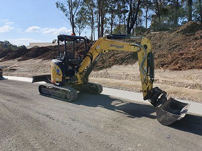 A small yellow excavator is parked on the side of a road.