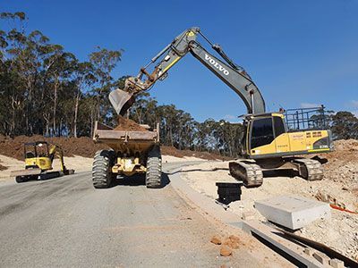 A volvo excavator is loading dirt into a dump truck.