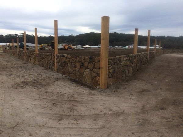 A stone wall with wooden posts surrounding it