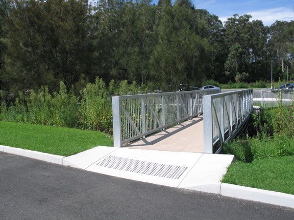 A bridge over a grassy area with trees in the background