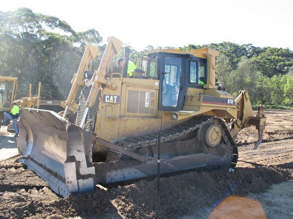 A cat bulldozer is parked in a dirt field