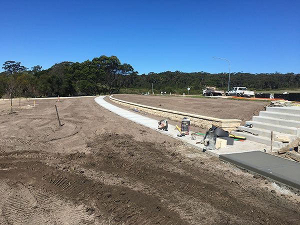 A road is being built in a dirt field with trees in the background.