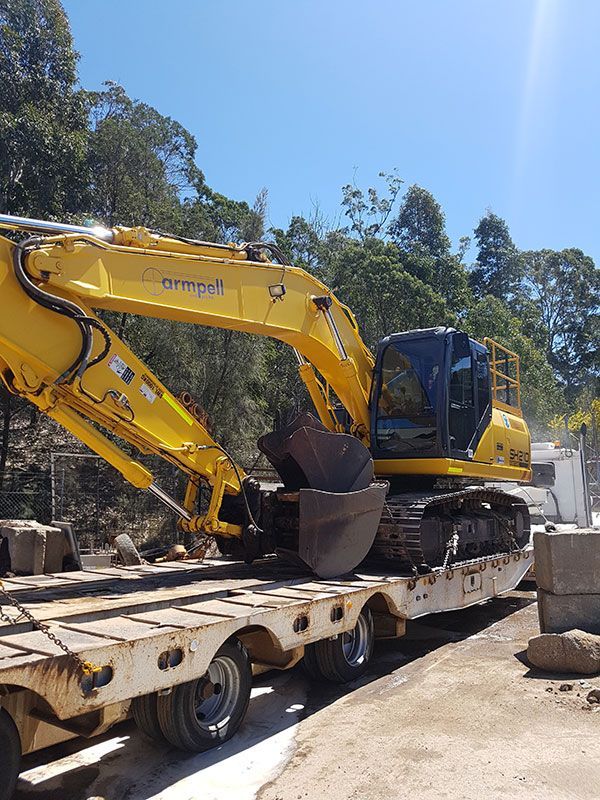 A yellow excavator is sitting on top of a trailer.