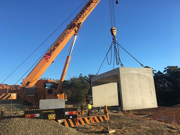An orange crane is lifting a large concrete box