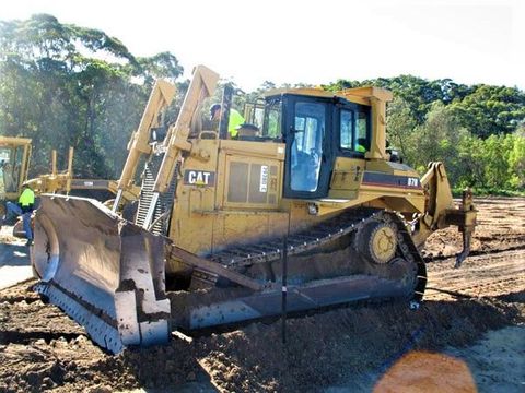 A yellow cat bulldozer is parked in a dirt field