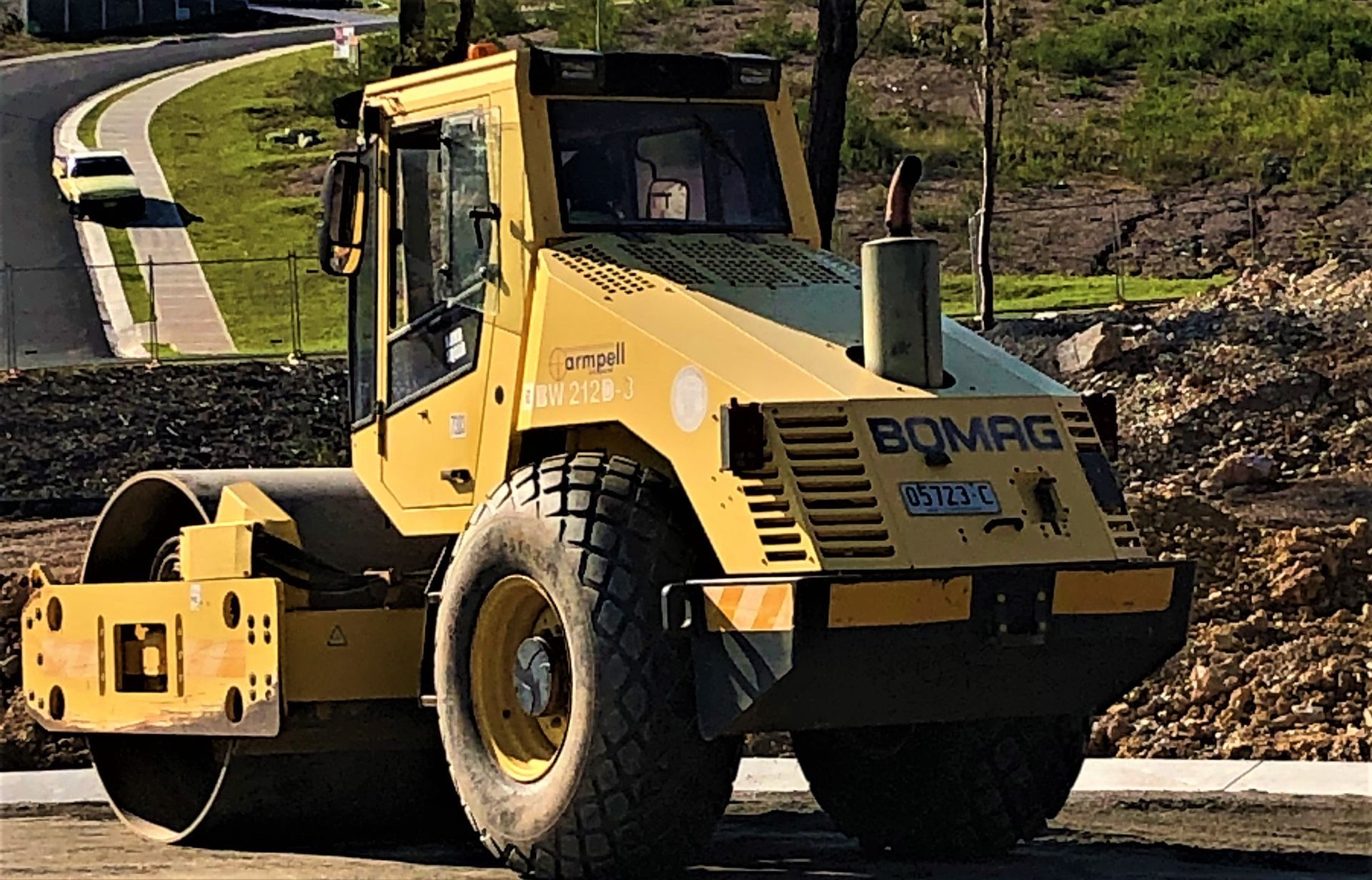 A yellow bomag roller is parked on the side of the road